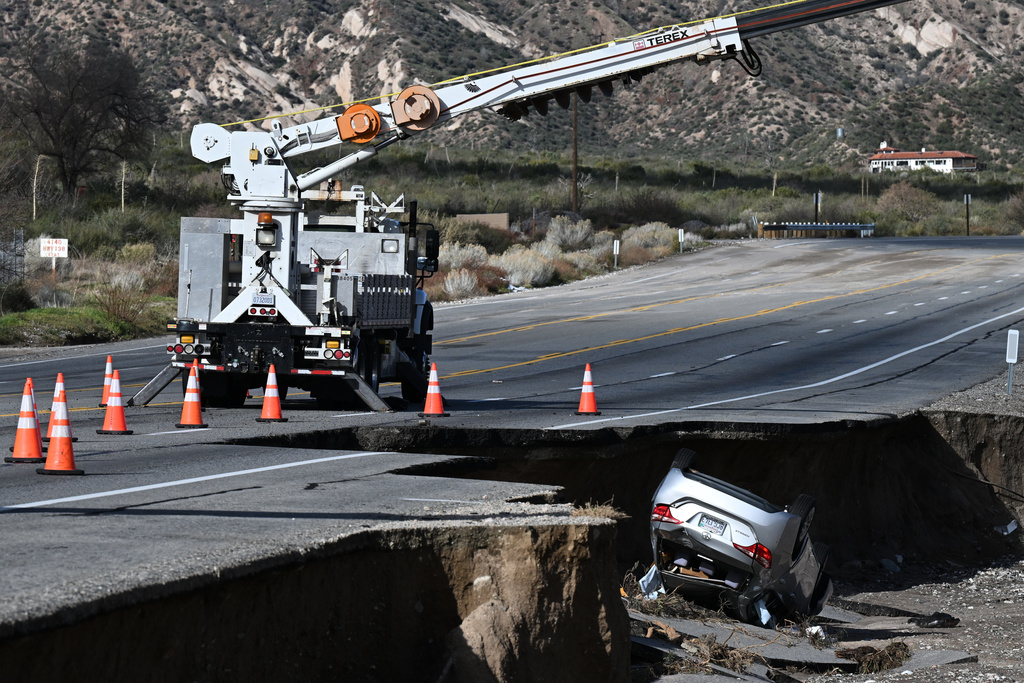 A car is flipped over along a storm-damaged road after a series of storms on Thursday, Dec. 25, 2025, near Phelan, Calif. (AP Photo/William Liang)