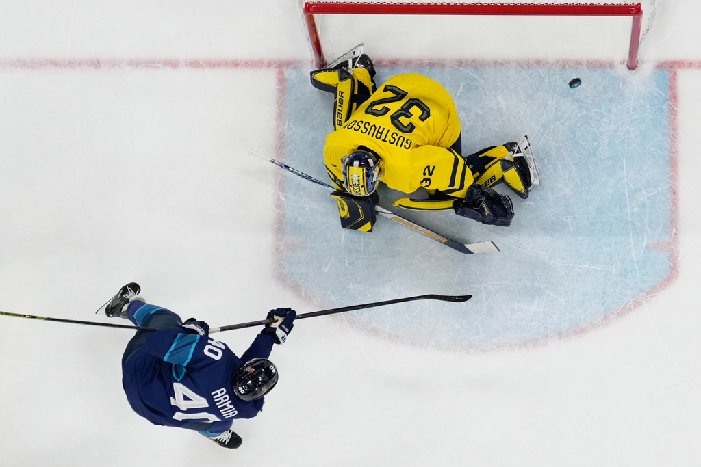 Finland's Joel Armia, left, scores his sides third goal past Sweden's goalkeeper Filip Gustavsson during a preliminary round match of men's ice hockey between Finland and Sweden at the 2026 Winter Olympics, in Milan, Italy, Friday, Feb. 13, 2026. (AP Photo/Petr David Josek)