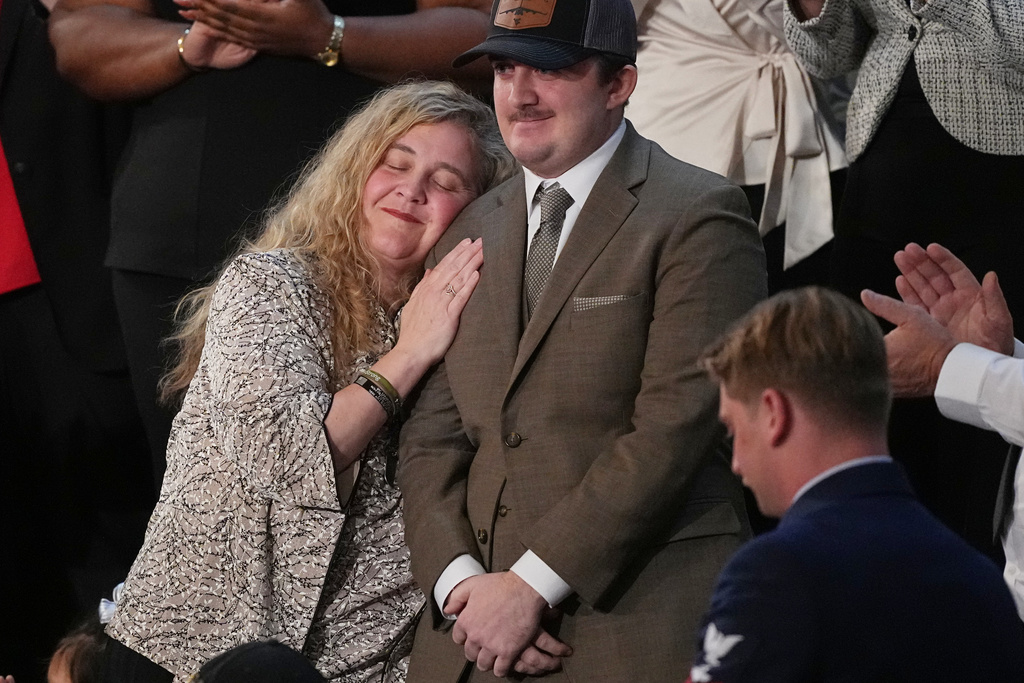 West Virginia National Guard Staff Sgt. Andrew Wolfe stands with his mother Melody as President Donald Trump delivers the State of the Union address to a joint session of Congress in the House chamber at the U.S. Capitol in Washington, Tuesday, Feb. 24, 2026. (AP Photo/Matt Rourke)