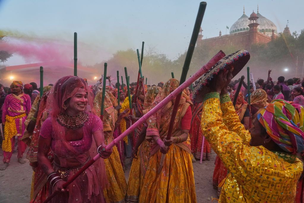 A member of transgender community with other women devotees symbolically beat men with wooden sticks to mark Lathmar Holi during Holi festival celebrations at the Shri Krishna Janmabhoomi Temple complex in Mathura, India, on Feb. 27, 2026. (AP Photo/Manish Swarup)