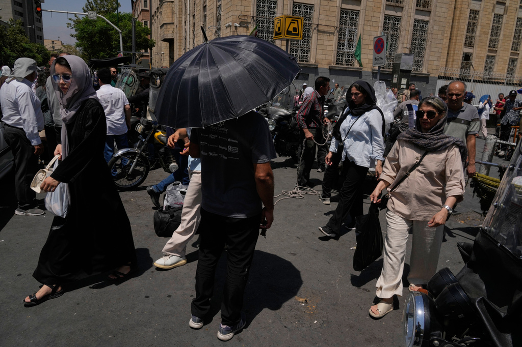 A man shelters from the sun under an umbrella as he stands at an intersection around Tehran's traditional main bazaar, Iran, Thursday, July 16, 2026. (AP Photo/Vahid Salemi)