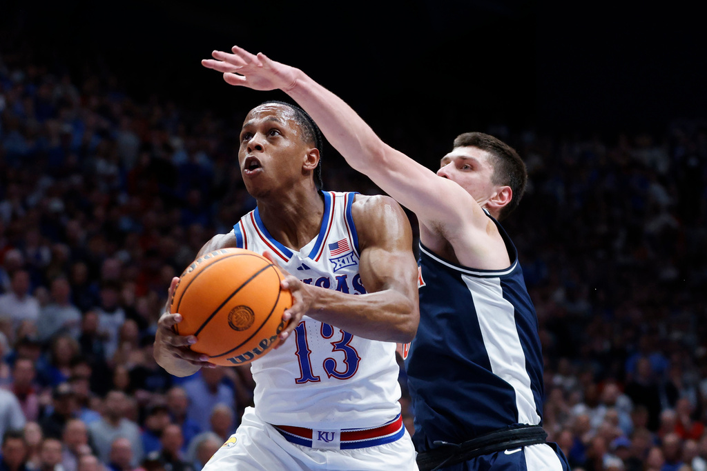 Kansas guard Elmarko Jackson (13) attempts to score as Arizona forward Ivan Kharchenkov, right, defends during the first half of an NCAA college basketball game, Monday, Feb. 9, 2026, in Lawrence, Kan. (AP Photo/Colin E. Braley)