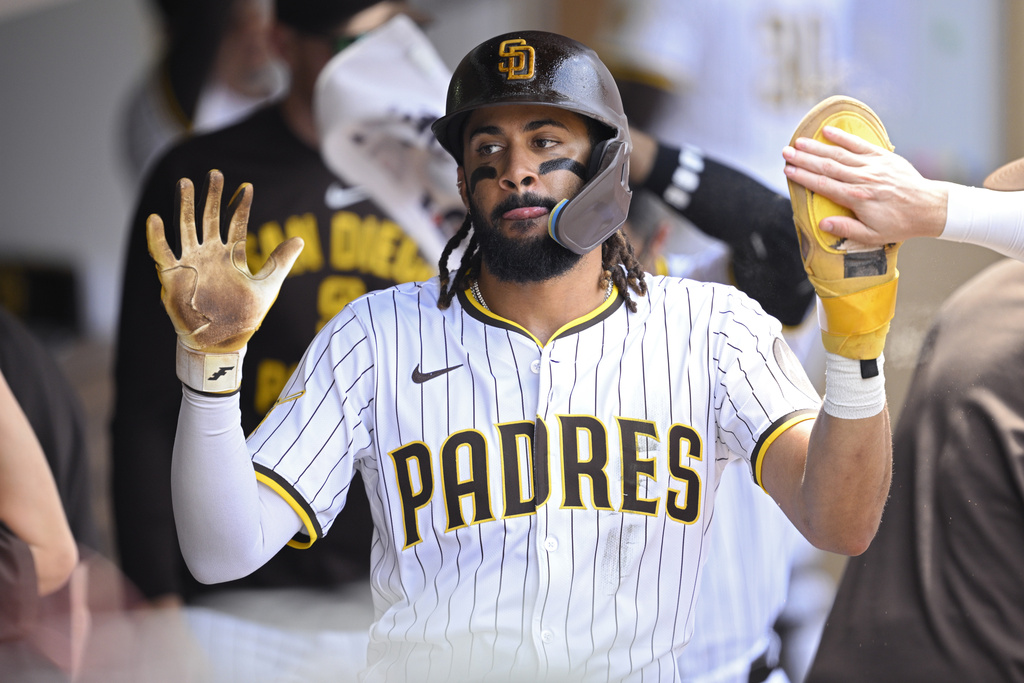 San Diego Padres' Fernando Tatis Jr. is congratulated in the dugout after scoring on a single by Manny Machado during the fourth inning of a baseball game against the San Francisco Giants, Thursday, Aug. 21, 2025, in San Diego. (AP Photo/Orlando Ramirez)