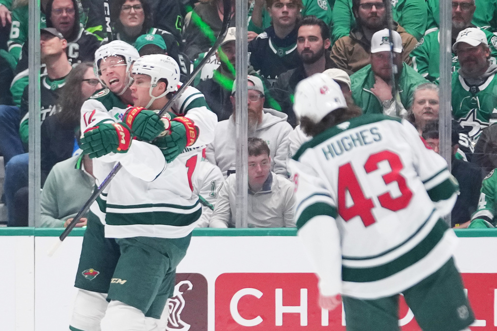 Minnesota Wild left wing Matt Boldy, left, congratulates Joel Eriksson Ek, center, after his power play goal against the Dallas Stars during the first period in Game 1 of a first-round NHL Stanley Cup playoffs hockey series, Saturday, April 18, 2026, in Dallas, Texas. (AP Photo/Julio Cortez)