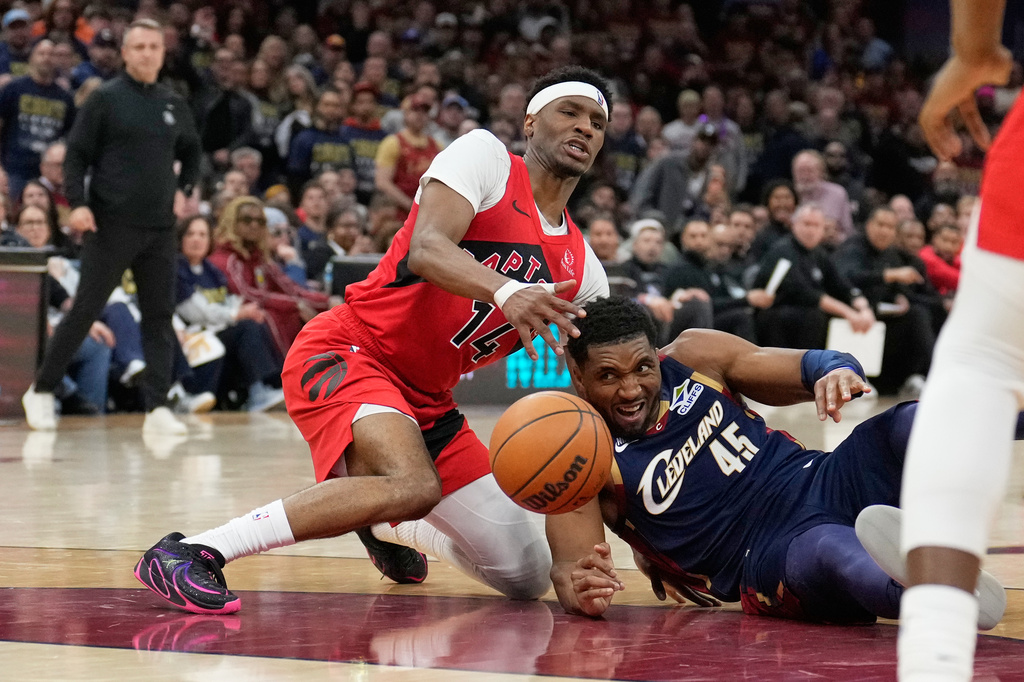 Toronto Raptors guard Ja'kobe Walter (14) and Cleveland Cavaliers guard Donovan Mitchell (45) reach for the ball in the second half in Game 2 of a first-round NBA basketball playoffs series in Cleveland, Monday, April 20, 2026. (AP Photo/Sue Ogrocki)