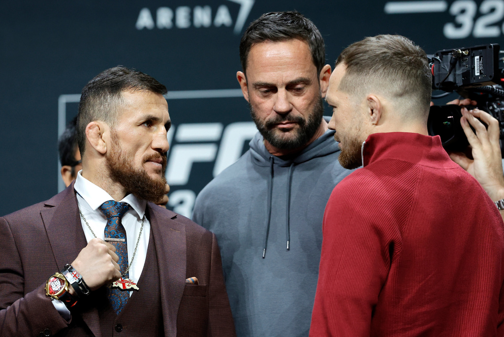 UFC bantamweight champion Merab Dvalishvili, left, of Georgia, faces off with challenger Petr Yan, of Russia, as UFC matchmaker Mick Maynard looks on during a news conference promoting UFC 323, Thursday, Dec. 4, 2025, in Las Vegas. (Steve Marcus/Las Vegas Sun via AP)