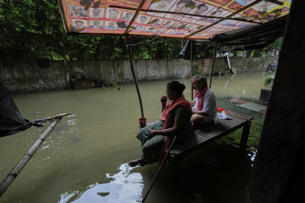 A couple drinks tea sitting in front of their inundated house after the river Yamuna, swollen by incessant rain in the higher regions, overran its banks, in New Delhi, India, Friday, Sept. 5, 2025. (AP Photo/Manish Swarup)