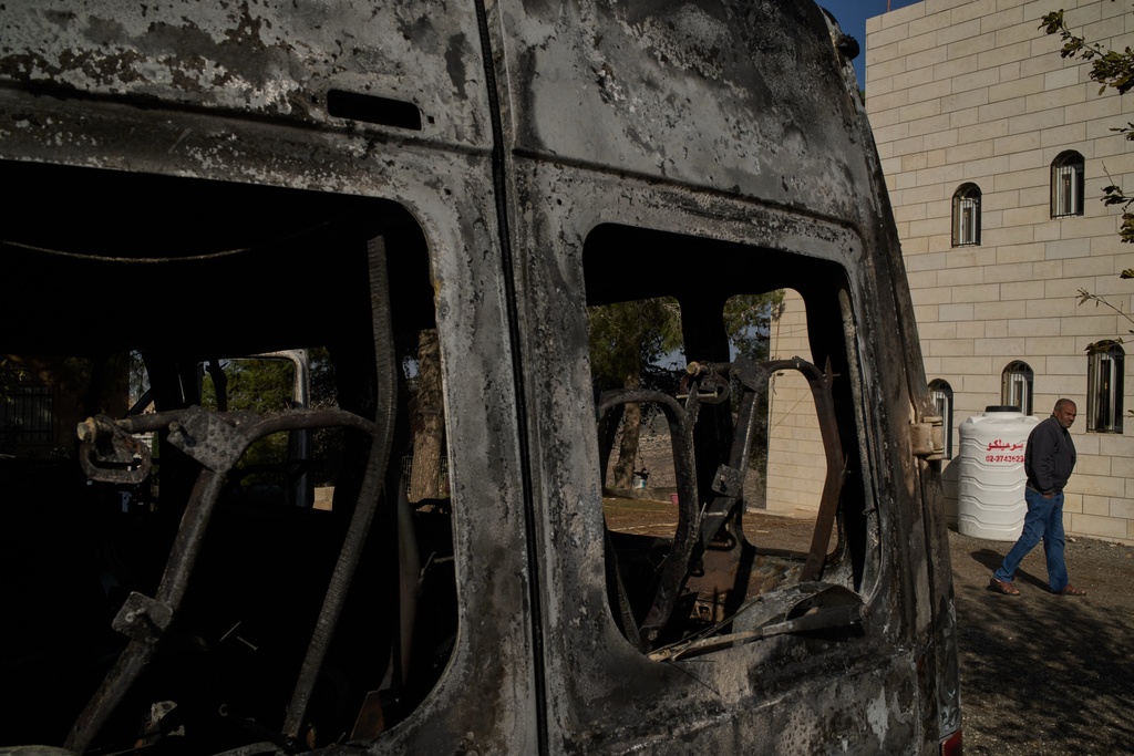 Moussab Mshala walks past a vehicle burned during an attack by Israeli settlers, in front of his house in the West Bank village of al-Jab'a, near Bethlehem, Tuesday, Nov. 18, 2025. (AP Photo/Leo Correa)