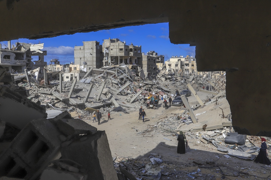 FILE - Palestinians walk through the rubble caused by the Israeli air and ground offensive in Rafah, southern Gaza Strip, Monday, Jan. 20, 2025. (AP Photo/Mariam Dagga, File)