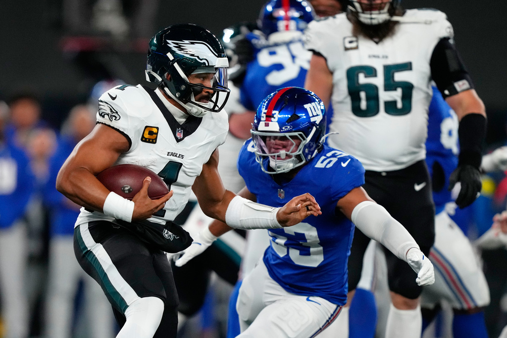 Philadelphia Eagles' Jalen Hurts, left, tries to get [past New York Giants' Darius Muasau during the first half of an NFL football game Thursday, Oct. 9, 2025, in East Rutherford, N.J. (AP Photo/Yuki Iwamura)