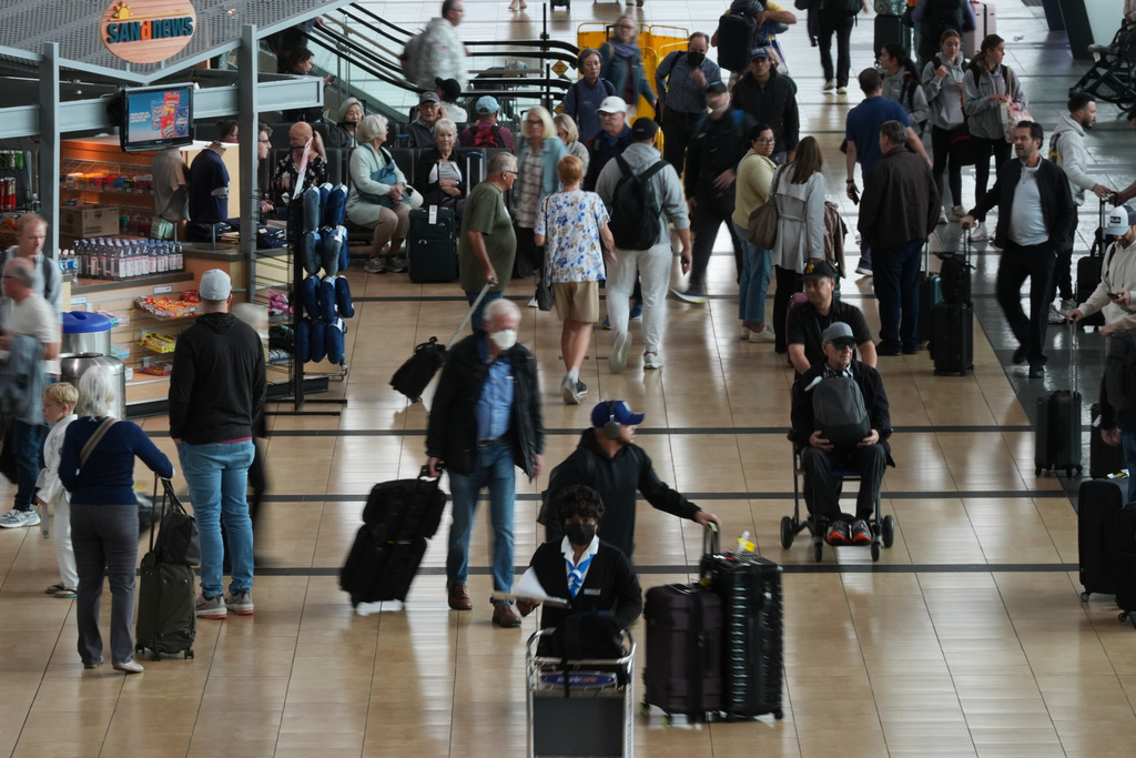 People make their way through a terminal at San Diego International Airport Saturday, Nov. 8, 2025, in San Diego. (AP Photo/Gregory Bull)