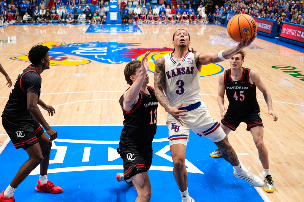 Kansas guard Tre White (3) gets past Davidson guard Hunter Adam (12) to put up a shot during the first half of an NCAA college basketball game Monday, Dec. 22, 2025, in Lawrence, Kan. (AP Photo/Charlie Riedel)
