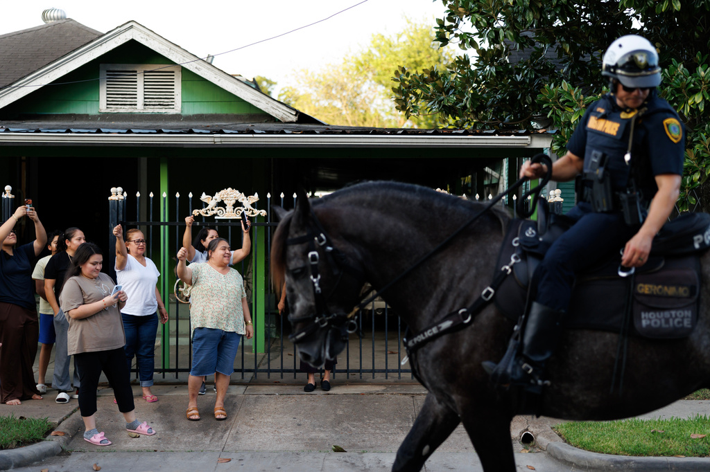 Neighbors cheer as marchers walk past during a vigil for Lorenzo Salgado Araujo, a Mexican national fatally shot by a federal immigration agent a day prior, Wednesday, July 8, 2026, in Houston. (AP Photo/Mark Felix)