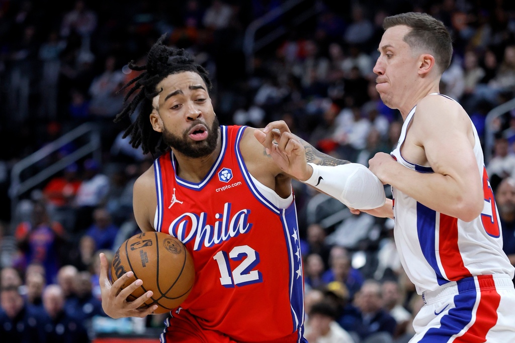 Philadelphia 76ers forward Trendon Watford (12) drives against Detroit Pistons forward Duncan Robinson during the first half of an NBA basketball game, Thursday, March 12, 2026, in Detroit. (AP Photo/Duane Burleson)