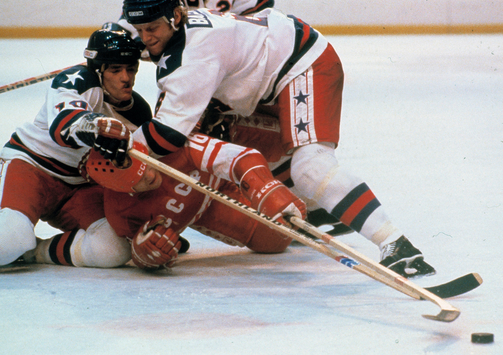 United States' hockey players Mark Johnson, left and Bill Baker, right, battle Soviet Union's Vladimir Petrov (16) for the puck during a medal round match at the 1980 Winter Olympics in Lake Placid, N.Y., Feb. 22, 1980. (AP Photo/File)