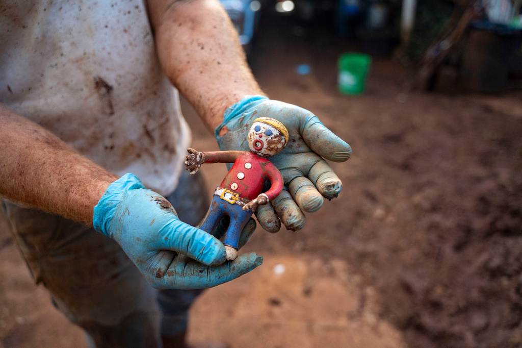 Nate Knaggs holds a mud-covered Mr. Bill toy he recovered from flood debris at his home, Tuesday, March 24, 2026, in Haleiwa, Hawaii. (AP Photo/Mengshin Lin)