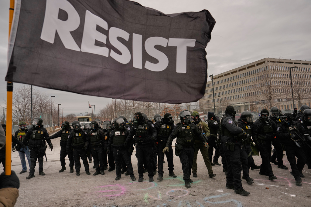 Federal immigration officers confront protesters outside Bishop Henry Whipple Federal Building, Thursday, Jan. 15, 2026, in Minneapolis. (AP Photo/John Locher)