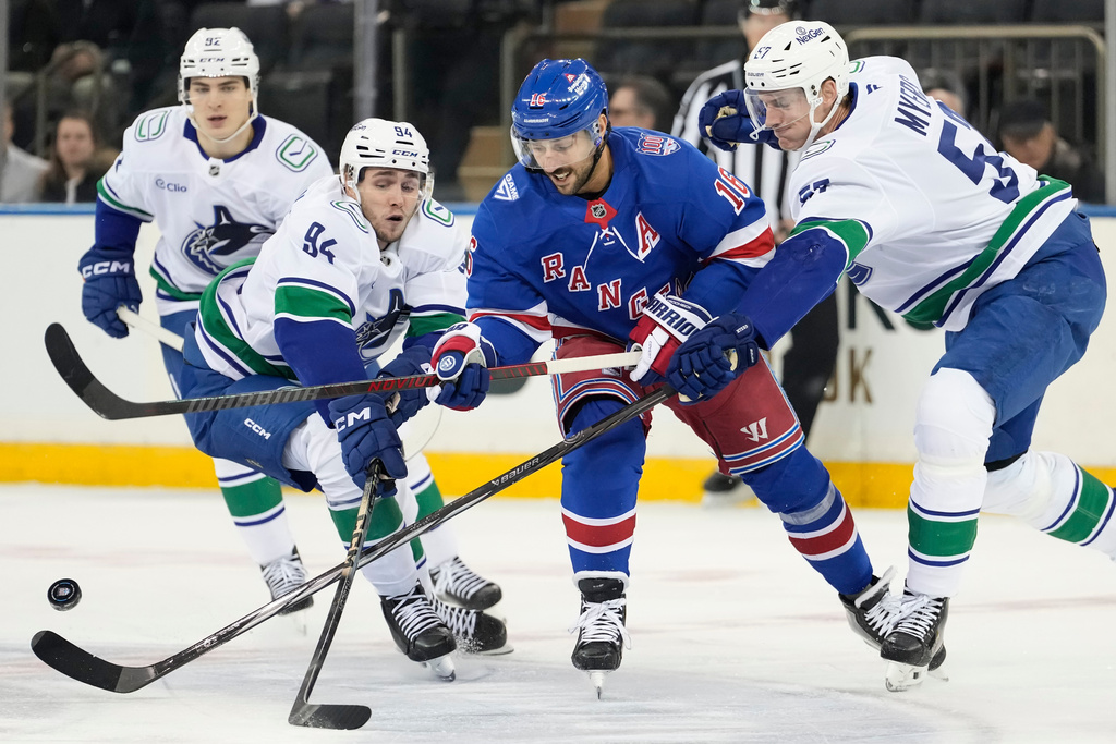 New York Rangers center Vincent Trocheck (16) fights for control of the puck with Vancouver Canucks defenseman Tyler Myers (57) and Vancouver Canucks center Linus Karlsson (94) during the first period of an NHL hockey game, Tuesday, Dec. 16, 2025, in New York. (AP Photo/Yuki Iwamura)