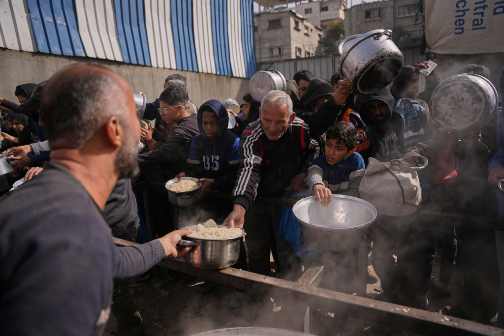 Palestinians receive donated food at a community kitchen in Nuseirat, in central Gaza Strip, Saturday, Jan. 24, 2026. (AP Photo/Abdel Kareem Hana)