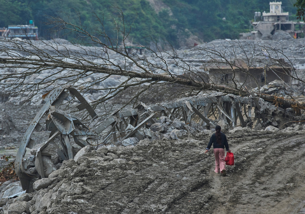 A woman walks past a damaged bridge and trees left by a flash flood on the bank of the Trishuli River in Nuwakot district, Nepal, Wednesday, Sept. 23, 2026. (AP Photo/Niranjan Shrestha)