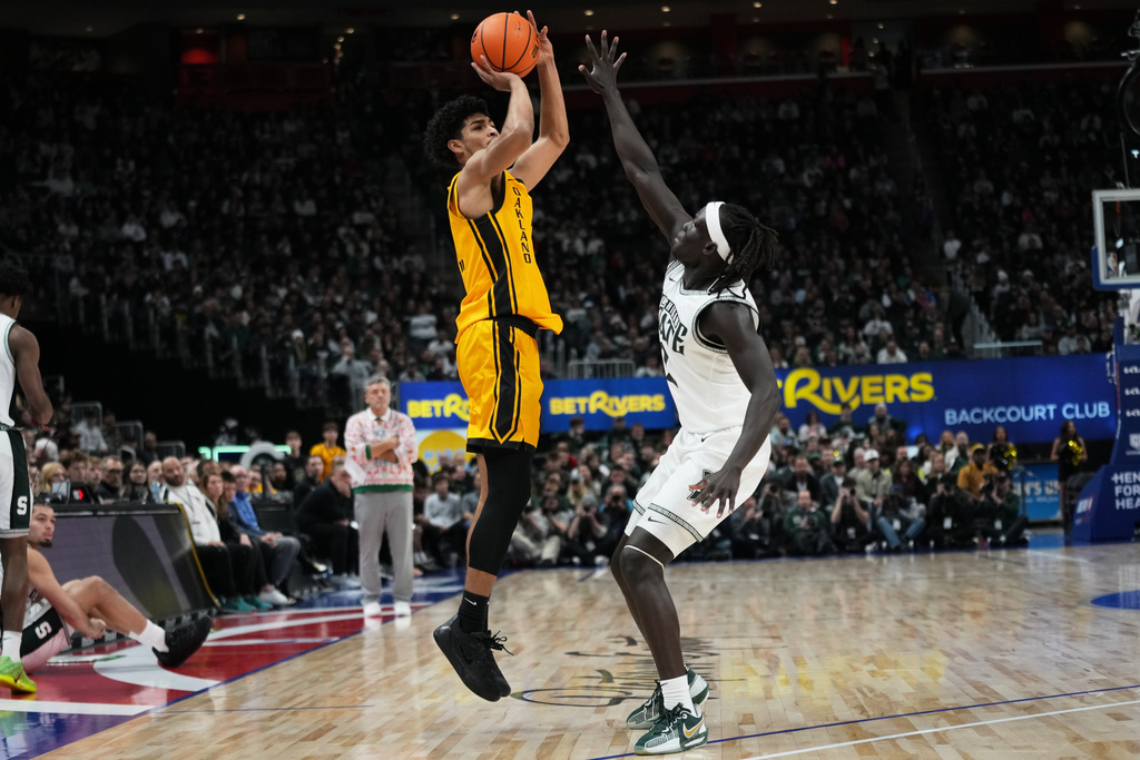 Oakland guard Brett White II, left, shoots against Michigan State guard Kur Teng during the first half of an NCAA college basketball game, Saturday, Dec. 20, 2025, in Detroit. (AP Photo/Ryan Sun)