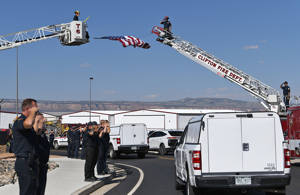 Firefighters salute as two trucks carrying the bodies of three firefighters killed while fighting the Snyder Fire are driven past in Grand Junction, Colo. Sunday, June 28, 2026. (Gretel Daugherty via AP)