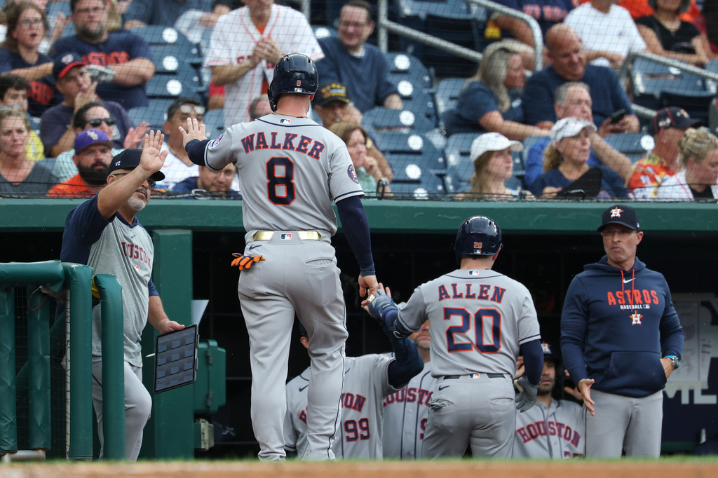 Houston Astros' Christian Walker (8) is greeted in the dugout after scoring a run on a sacrifice fly hit by Nick Allen (20) hit off Washington Nationals pitcher Andrew Alvarez during the second inning of a baseball game, Tuesday, July 7, 2026, in Washington. (AP Photo/Terrance Williams)
