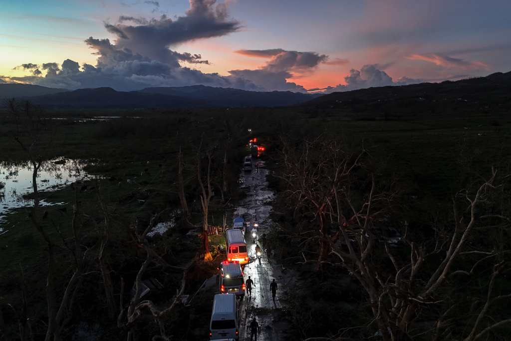 A convoy carrying aid to Black River, which was hit by Hurricane Melissa, makes its way through Holland Bamboo, Jamaica, Wednesday, Oct. 29, 2025, where downed trees and debris partially block the road. (AP Photo/Matias Delacroix)
