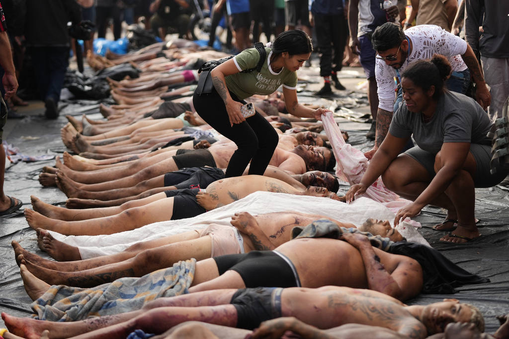 EDS NOTE: GRAPHIC CONTENT - Relatives look at the bodies of people killed the day before during a police raid targeting the Comando Vermelho gang in the Complexo da Penha favela of Rio de Janeiro, Brazil, Wednesday, Oct. 29, 2025..(AP Photo/Silvia Izquierdo)