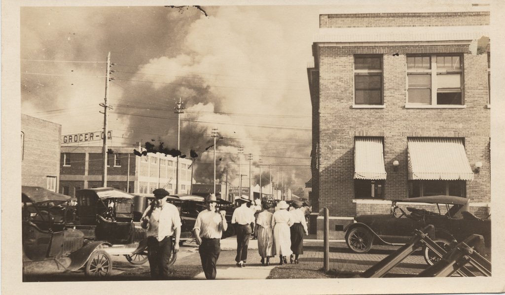 This photo provided by The University of Tulsa shows two armed men walking away from a billowing cloud of smoke during the Tulsa Race Massacre, June 1, 1921, in Tulsa, Okla. (The University of Tulsa McFarlin Library/Department of Special Collections and University Archives via AP)