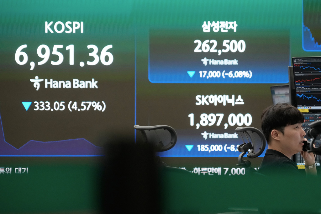 A currency trader talks on the phone near a screen showing the Korea Composite Stock Price Index (KOSPI), SK Hynix and Samsung Electronics Co. stock price at the foreign exchange dealing room of the Hana Bank headquarters in Seoul, South Korea, Thursday, July 16, 2026. (AP Photo/Ahn Young-joon)