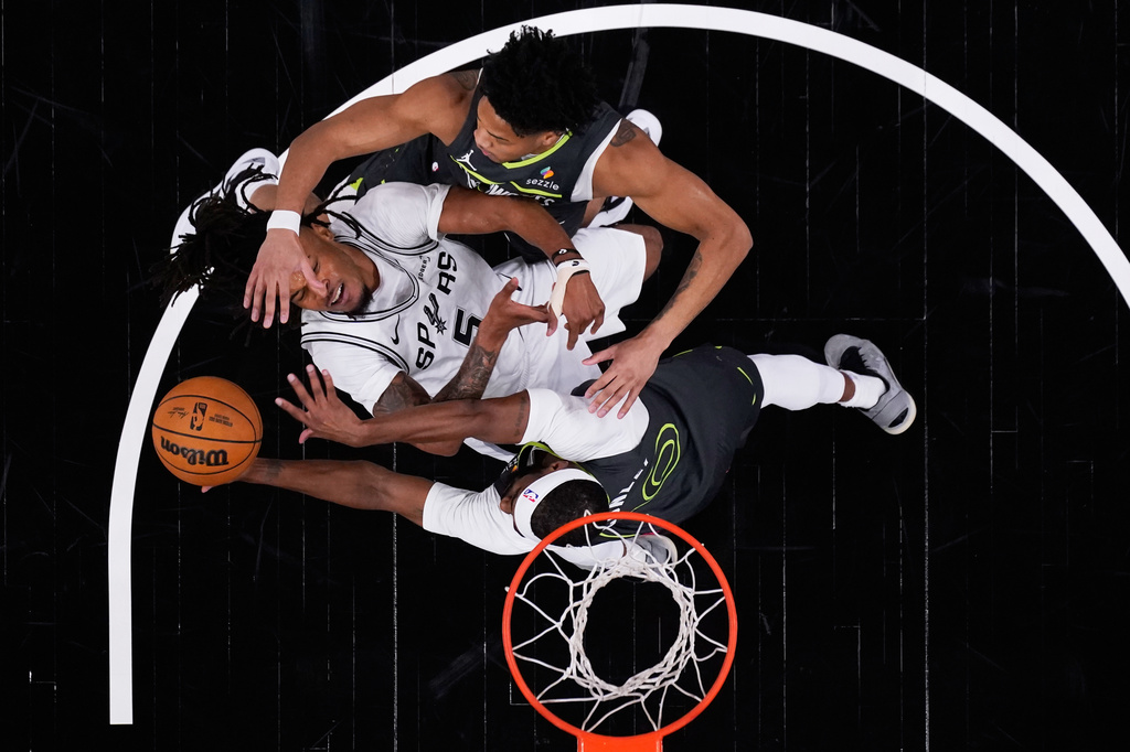San Antonio Spurs guard Stephon Castle (5) is blocked by fouled by Minnesota Timberwolves guard Mike Conley (10) and guard Terrence Shannon Jr. (1) during the first half in Game 2 of a second-round NBA playoffs basketball series in San Antonio, Wednesday, May 6, 2026. (AP Photo/Eric Gay)