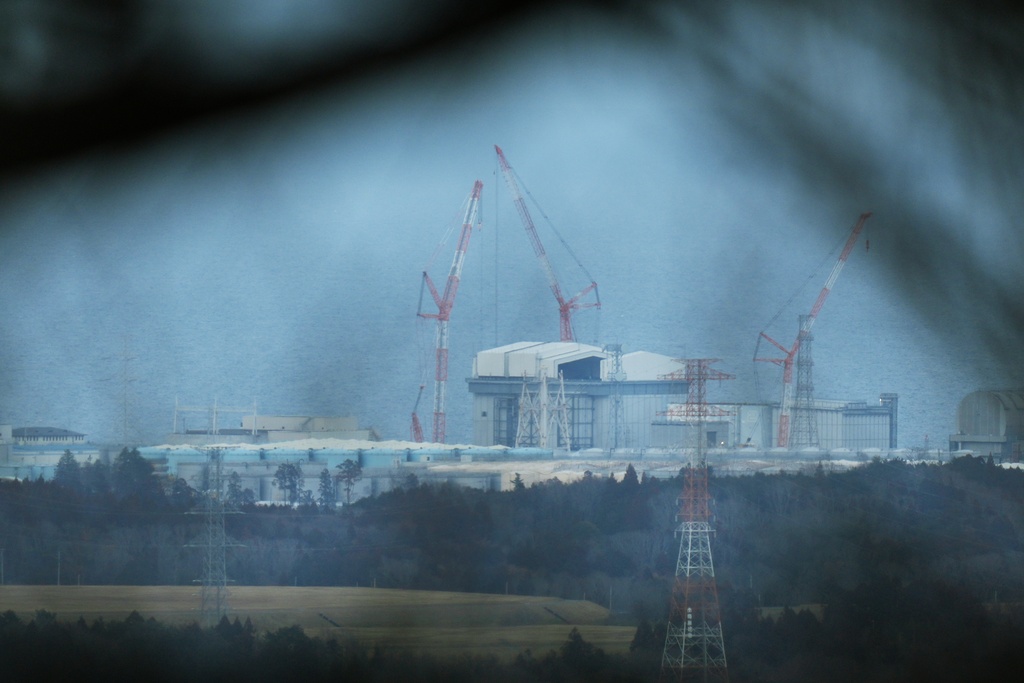The Fukushima Daiichi nuclear power plant, damaged by a March 11, 2011, earthquake and tsunami, is seen through branches from a hill in Tomioka, northeastern Japan, Tuesday, Feb. 10, 2026. (AP Photo/Hiro Komae)