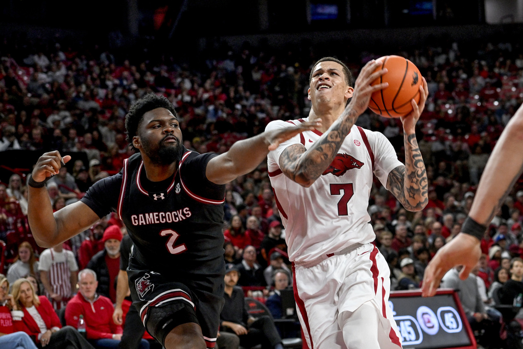 Arkansas forward Trevon Brazile (7) drives past South Carolina forward Christ Essandoko (2) during the second half of an NCAA college basketball game Wednesday, Jan. 14, 2026, in Fayetteville, Ark. (AP Photo/Michael Woods)