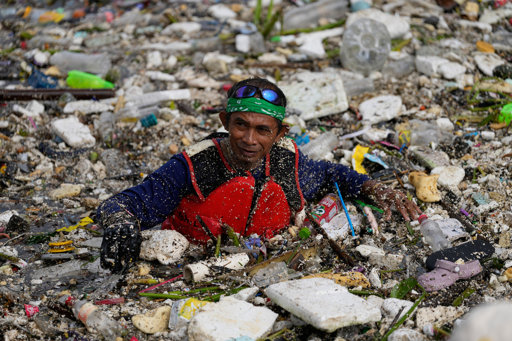 A worker tries to clear a sea of garbage and debris brought by intense monsoon rains at the Redemptorist Water Channel in Paranaque city, Metro Manila, Philippines Tuesday, Aug. 11, 2026. (AP Photo/Aaron Favila)