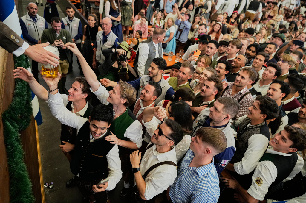 Visitors wait for beer at the opening of the 191st Oktoberfest beer festival in Munich, Germany, Saturday, Sept.19, 2026. (AP Photo/Matthias Schrader)