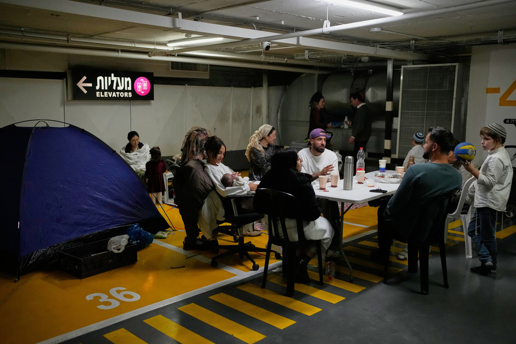 People take shelter in an underground parking garage as air raid sirens warn of incoming missiles strike by Iran, in Tel Aviv, Israel, Saturday, Feb. 28, 2026. (AP Photo/Ohad Zwigenberg)