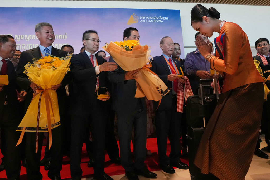 Cabin crew of the first commercial flight that landed receive flowers from government officials at the Techo International Airport during its official opening on the outskirts of Phnom Penh, Cambodia, Tuesday, Sept. 9,2025. (AP Photo/Heng Sinith)