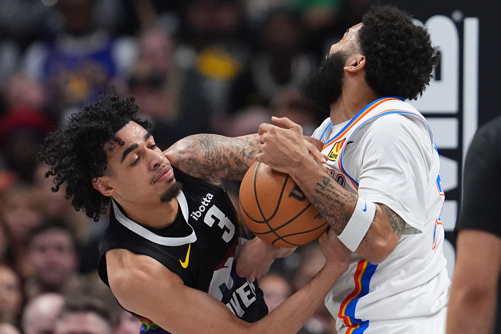Denver Nuggets guard Julian Strawther, left, fights for control of the ball with Oklahoma City Thunder forward Kenrich Williams, right, in the first half of an NBA basketball game Friday, April 10, 2026, in Denver. (AP Photo/David Zalubowski)