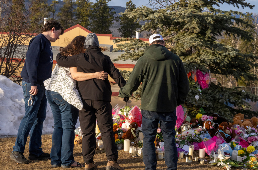 Residents hug as they place flowers at a memorial for the victims of Tuesday's mass shooting in Tumbler Ridge, British Columbia, Canada, on Thursday, Feb. 12, 2026. (Christinne Muschi/The Canadian Press via AP)