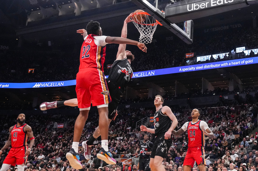 Toronto Raptors' Sandro Mamukelashvili, center right, dunks against New Orleans Pelicans' Derik Queen (22) during first-half NBA basketball game action in Toronto, Friday March 27 2026. (Chris Young/The Canadian Press via AP)