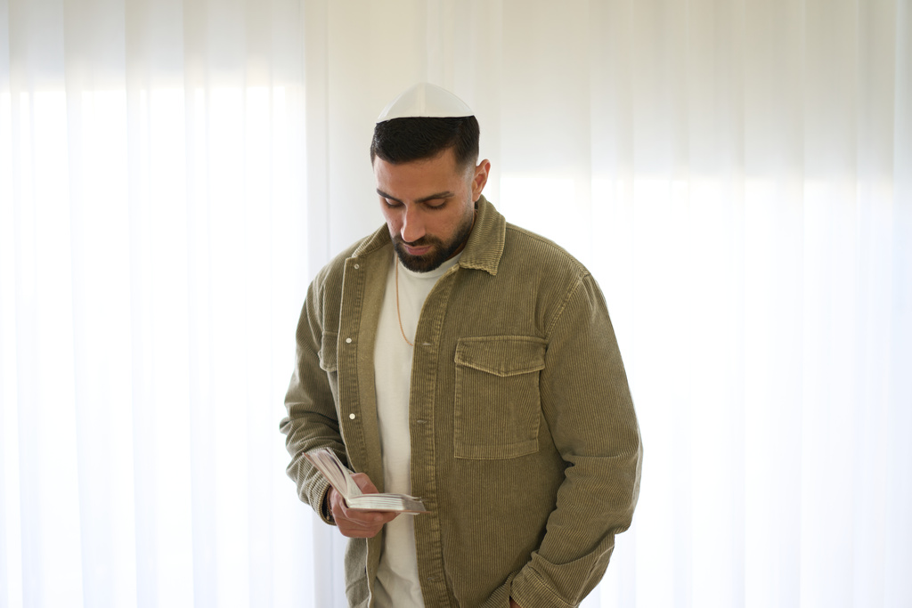 Segev Kalfon, an Israeli hostage who spent two years in captivity in a Hamas tunnel and was released from the Gaza Strip in a ceasefire deal on Oct. 13, reads from a holy book on at his home in Dimona, southern Israel, Tuesday, Dec. 23, 2025. (AP Photo/Ariel Schalit)