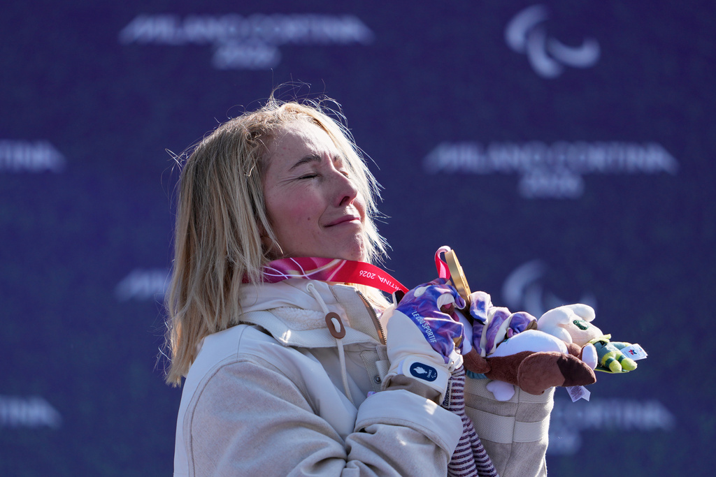 Cecile Hernandez, of France, stands on the podium after winning the gold medal in the women's snowboard cross SB-LL2 at the 2026 Winter Paralympics, in Cortina d'Ampezzo, Italy, Sunday, March 8, 2026. (AP Photo/Evgeniy Maloletka