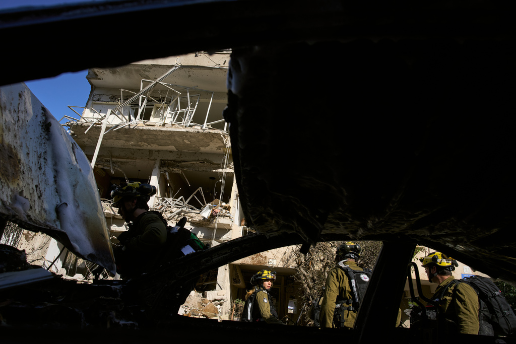 Israeli security forces and rescue teams inspect the site of an Iranian missile strike in Tel Aviv, Israel, Tuesday, March 24, 2026. (AP Photo/Oded Balilty)