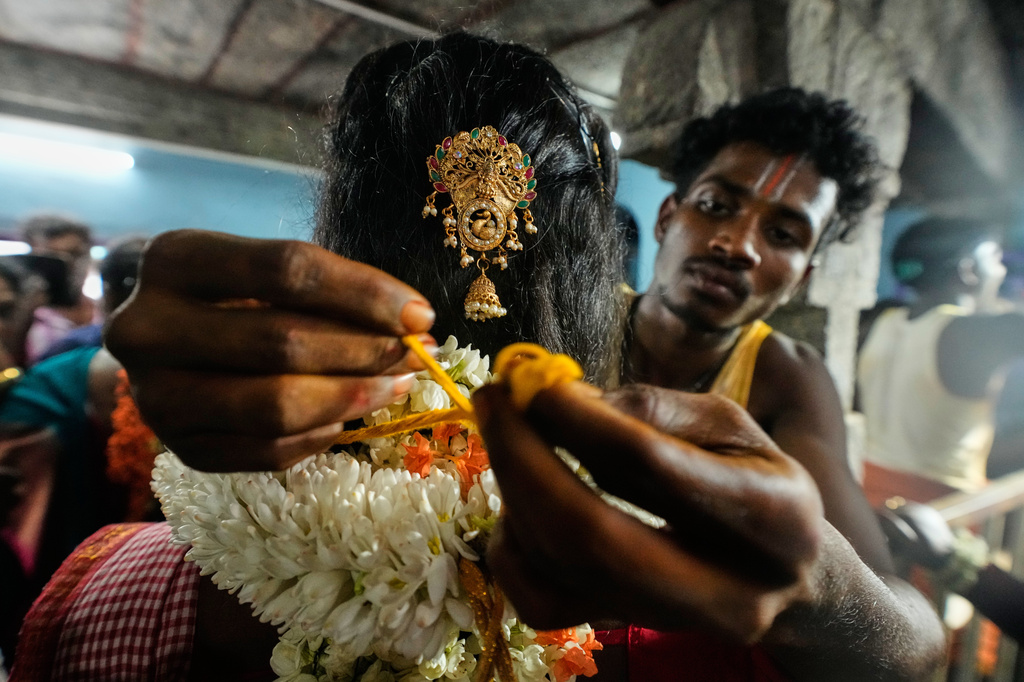 A priest ties a yellow sacred thread around the neck of a transgender participant symbolically marrying the Hindu god Aravan during the Koovagam festival in Kallakurichi district in the southern Indian state of Tamil Nadu, Tuesday, April 28, 2026. (AP Photo/Mahesh Kumar A.)
