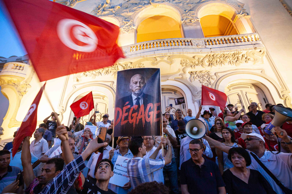 People take part in a protest against rising prices, declining purchasing power and shortages of basic goods in Tunis, Tunisia, Thursday, Aug. 20, 2026. Banner in French showing Preident Kais Saied reads "Leave". (AP Photo/Ons Abid)