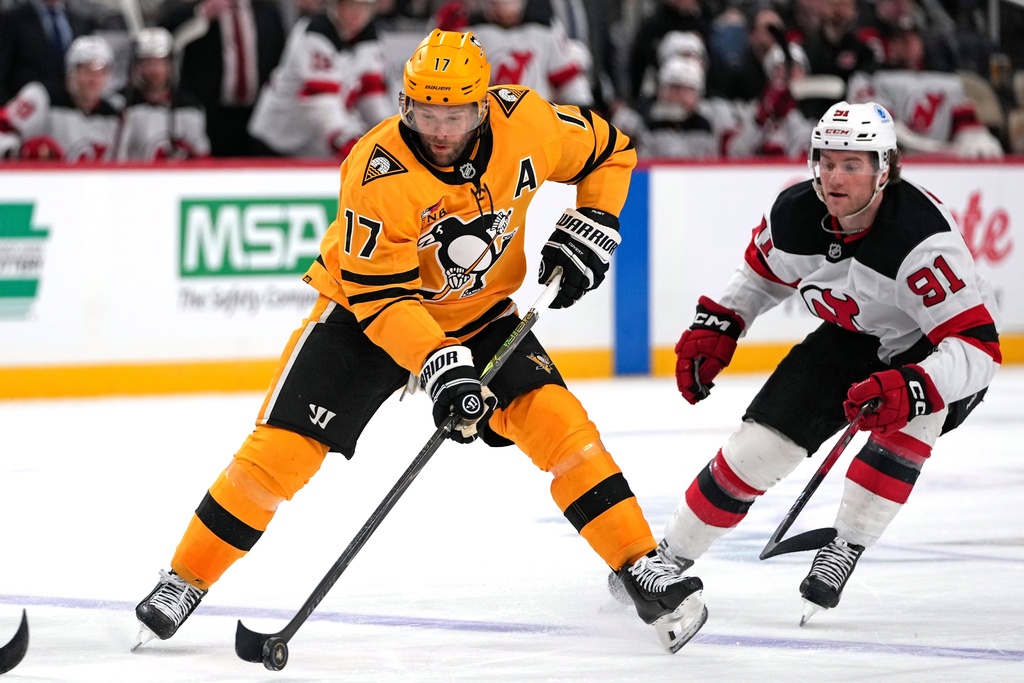 Pittsburgh Penguins' Bryan Rust (17) gets off a pass in front of New Jersey Devils' Dawson Mercer (91) during the second period of an NHL hockey game in Pittsburgh, Thursday, Feb. 26, 2026. (AP Photo/Gene J. Puskar)
