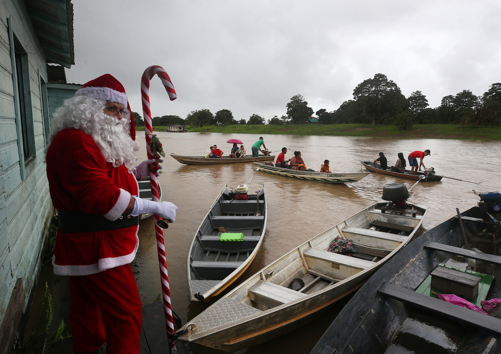 A man dressed as Santa Claus arrives to distribute Christmas gifts to children living in riverside communities in Careiro da Varzea, Brazil, Saturday, Dec. 20, 2025. (AP Photo/Edmar Barros)