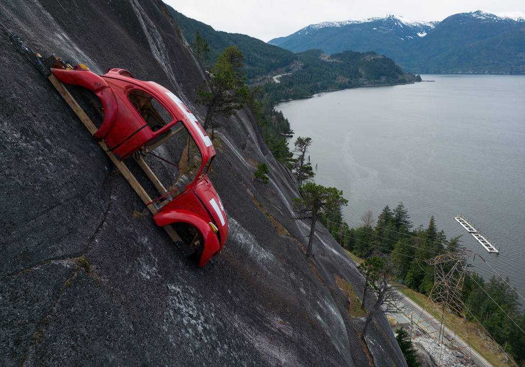 The shell of a Volkswagen Beetle hangs suspended on a cliff above the Sea-to-Sky Highway, in Squamish, British Columbia, Monday, April 6, 2026, after it appeared on the rock face last week with a large "E" on its roof, indicating that University of British Columbia engineering students carried out a long-standing tradition of placing the shell in difficult to reach locations. (Darryl Dyck/The Canadian Press via AP)