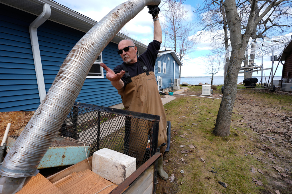 Tom Peterman cleans up outside his home from recent floods at Black Lake on Wednesday, April 29, 2026, in Grant Township, Mich. (AP Photo/Paul Sancya)